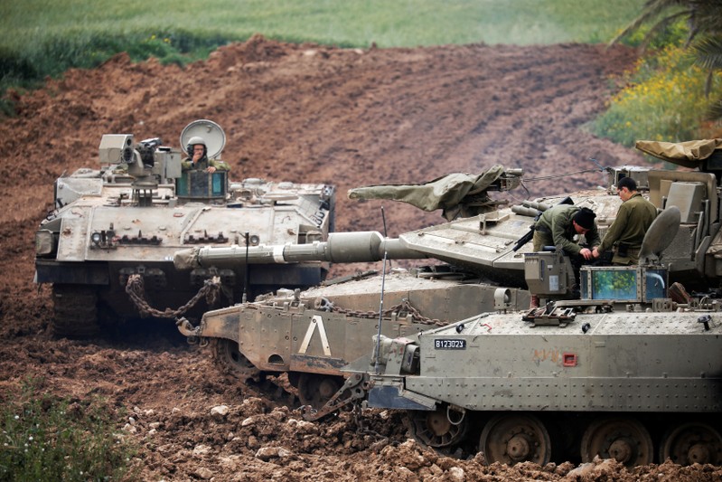Israeli soldiers are seen on top of an armoured personnel carrier (APC) near the border between Israel and Gaza on its Israeli side