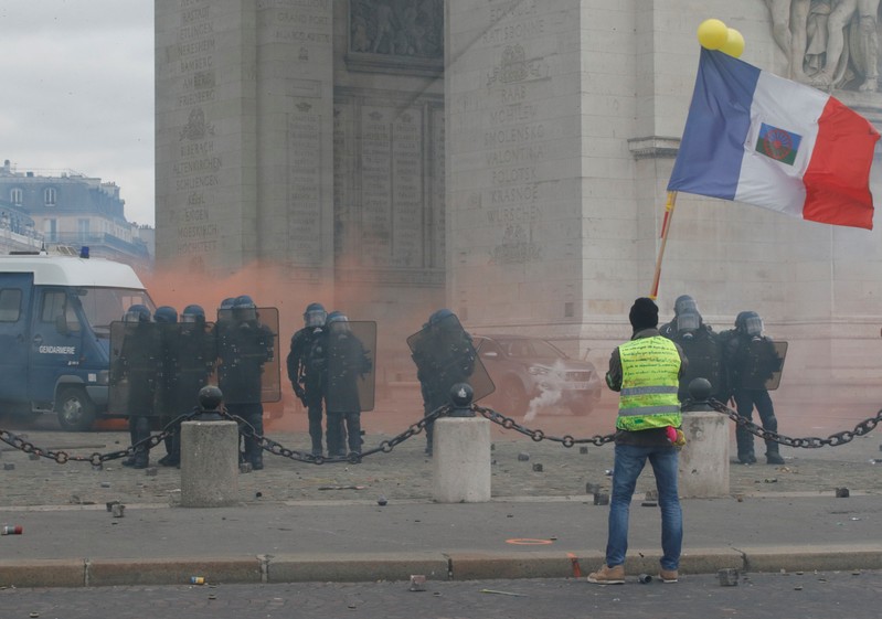 Protester wearing a yellow vest holds a flag during a demonstration by the