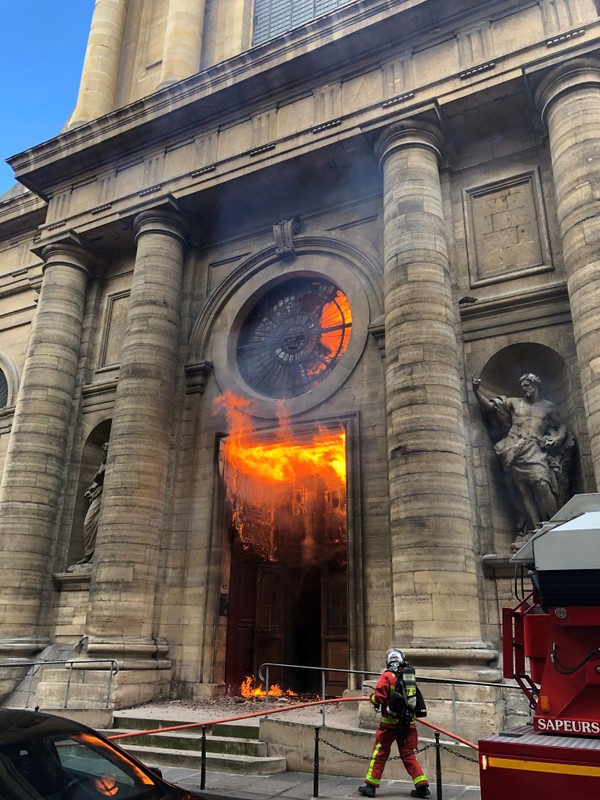 A member of the fire brigade reacts as Saint-Sulpice church is seen on fire in Paris