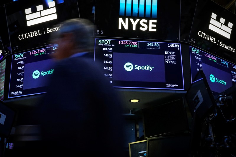 A trader passes by screens showing Spotify on the floor at the NYSE in New York