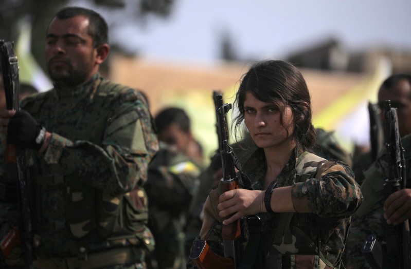 A fighter of Syrian Democratic Forces (SDF) holds her weapon as they announce the destruction of Islamic State's control of land in eastern Syria