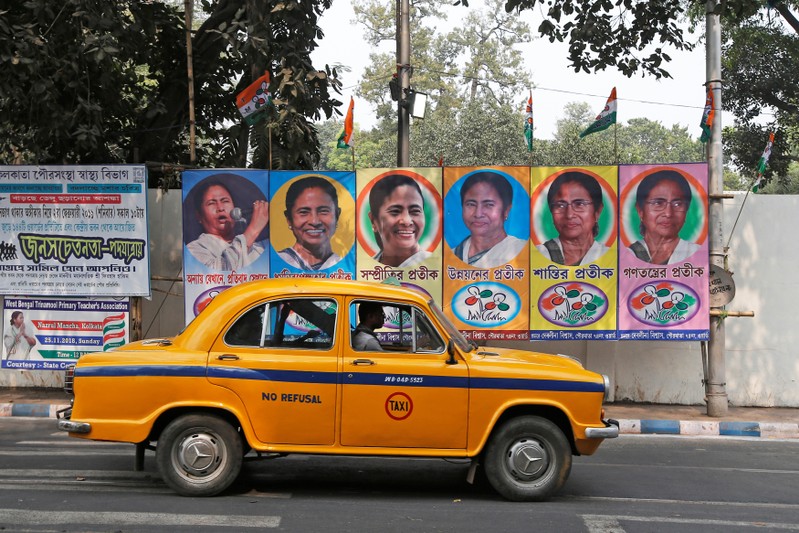 A taxi drives past a poster of Mamata Banerjee, Chief Minister of West Bengal state, in Kolkata
