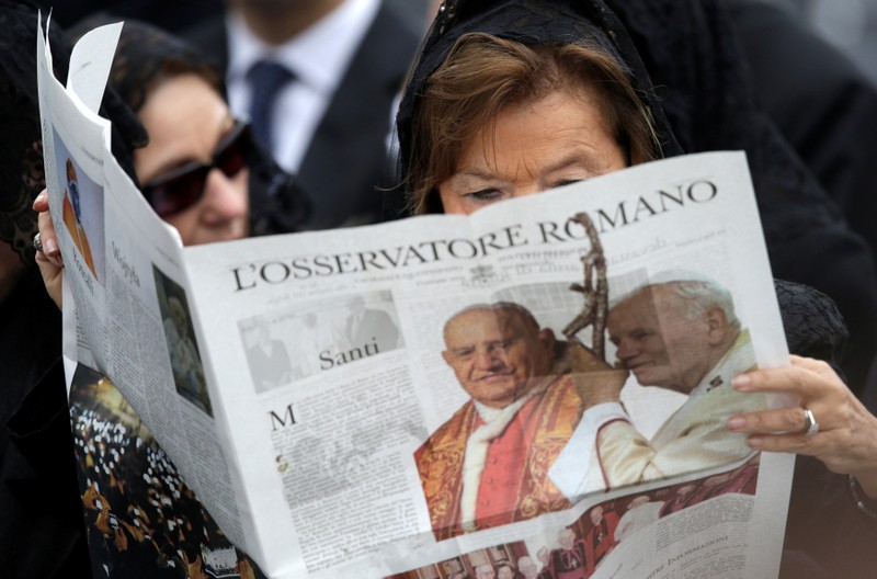 FILE PHOTO: A woman reads a copy of the Vatican newspaper L'Osservatore Romano as she waits for the canonisation ceremony in St Peter's Square at the Vatican