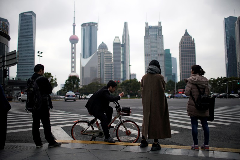 FILE PHOTO: People stand on the sidewalk at Lujiazui financial district in Pudong, Shanghai