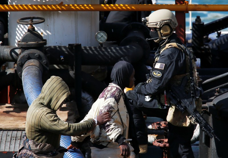 A Maltese special forces soldier guards a group of migrants on the merchant ship Elhiblu 1 after it arrived in Senglea