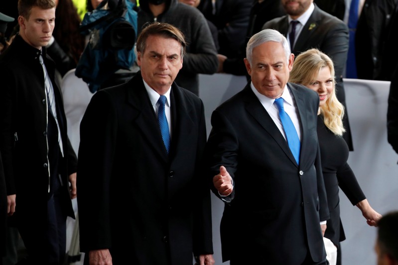 Israeli Prime Minister Benjamin Netanyahu gestures as he stands next to Brazilian President Jair Bolsonaro during a welcoming ceremony upon his arrival in Israel, at Ben Gurion International airport in Lod, near Tel Aviv, Israel