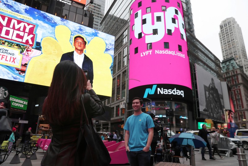 Brian Friedenberg, an intern for Lyft, has his picture taken in front of signage for Lyft as it is displayed at the NASDAQ MarketSite in Times Square in celebration of its initial public offering (IPO) on the NASDAQ Stock Market in New York