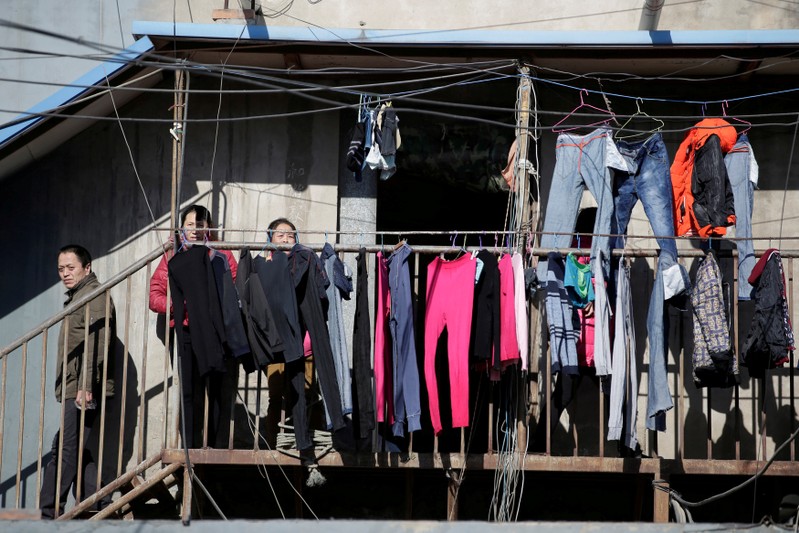 FILE PHOTO: People stand outside a low-cost dwelling at a village in Tongzhou district of Beijing