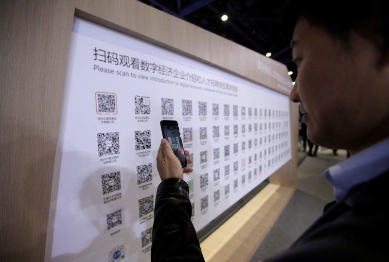 A man uses mobile phone to scan the QR codes for job-seeking information during an internet expo at the fifth WIC in Wuzhen