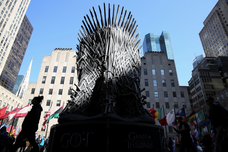 People walk past a large replica of the iron throne before the premiere of the final season of