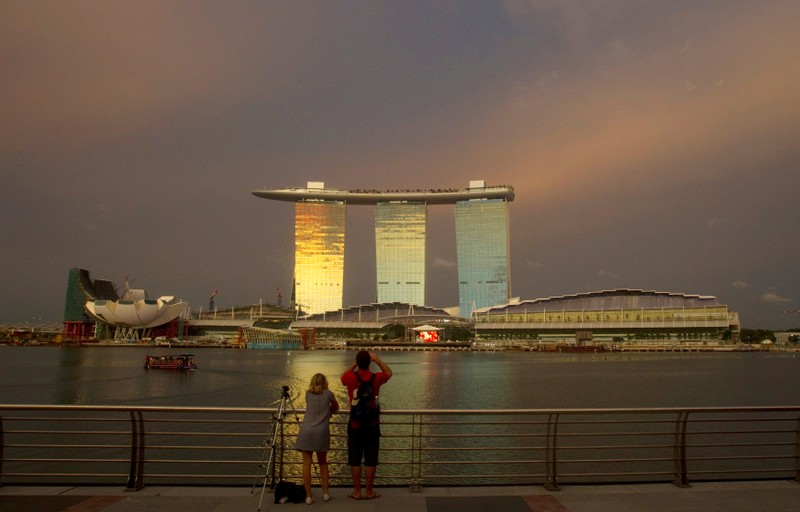 FILE PHOTO: File picture shows tourists standing at a promenade across the water from the Marina Bay Sands integrated resort in Singapore