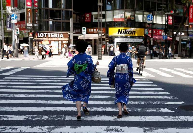 FILE PHOTO: Girls wearing the yukata, or casual summer kimono, run as they cross the road at a shopping district in Tokyo