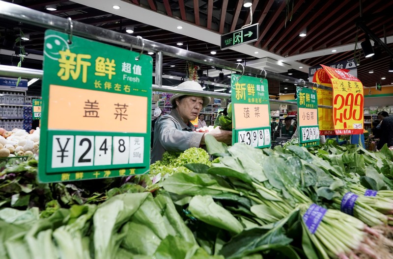 A woman selects vegetables at a supermarket in Beijing
