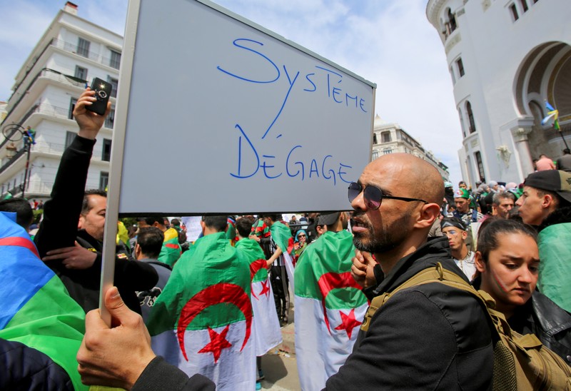 A man carries a sign during a protest seeking the departure of the ruling elite in Algiers