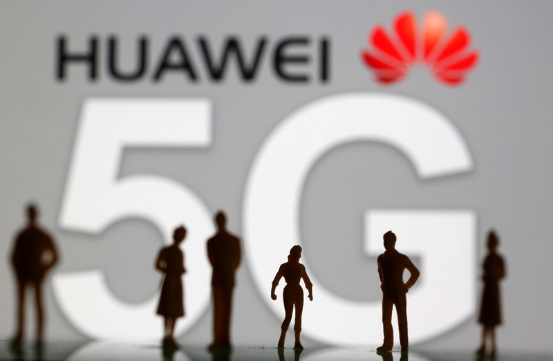FILE PHOTO: Small toy figures are seen in front of a displayed Huawei and 5G network logo in this illustration picture