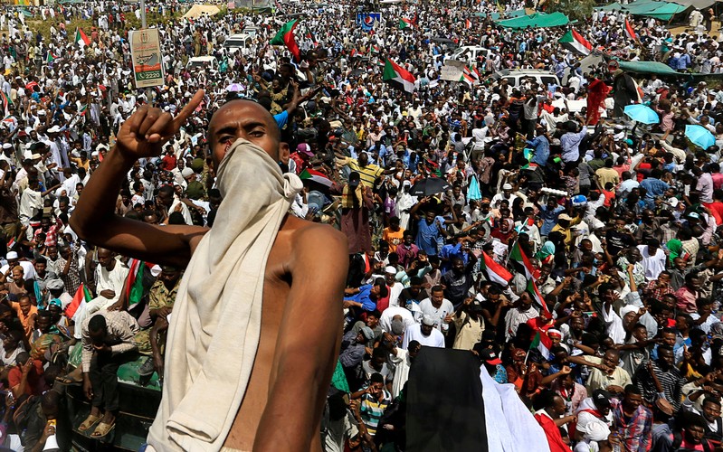 A Sudanese demonstrator gestures while riding atop a military truck as he protests against the army's announcement that President Omar al-Bashir would be replaced by a military-led transitional council, near Defence Ministry in Khartoum