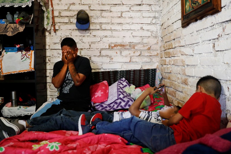 Arturo, a Mexican migrant, reacts next to his sons inside their house in Neutla