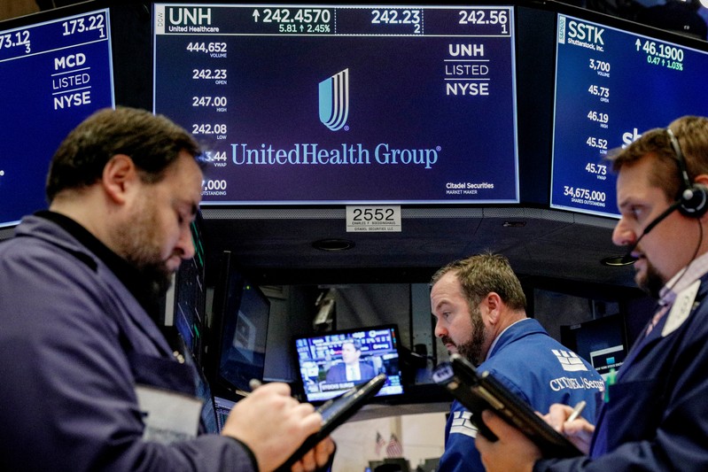 FILE PHOTO: Traders work at the post where UnitedHealth Group is traded on the floor of the NYSE in New York