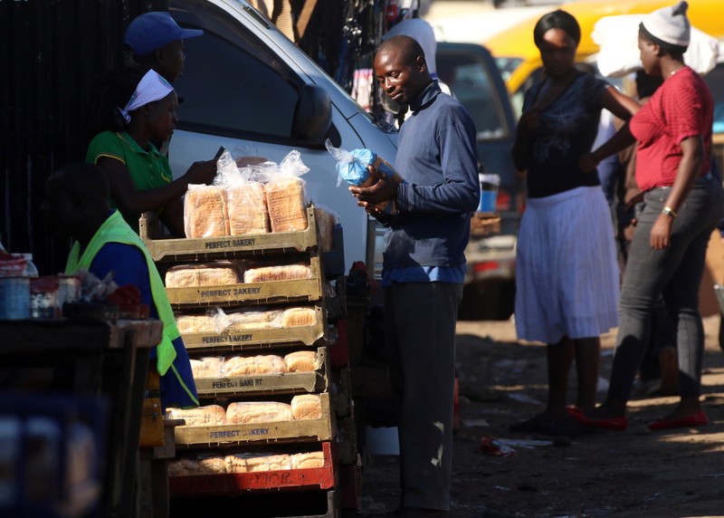 A man buys bread from a street vendor in Mbare township