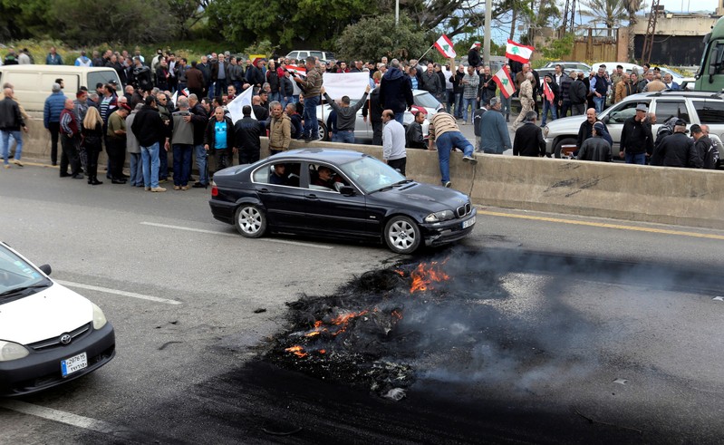 Retired army officers hold Lebanese flags as they block a highway during a protest in Naameh, south of Beirut