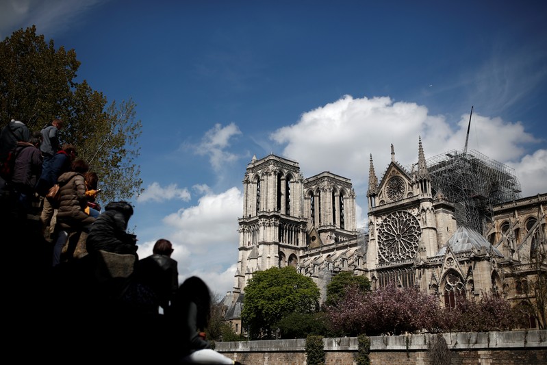 People look at Notre-Dame Cathedral two days after a massive fire devastated large parts of the gothic structure in Paris