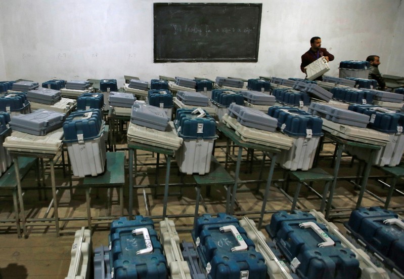 A polling officials holds an Electronic Voting Machine inside a strong room at a distribution centre ahead of the second phase of general election in Srinagar