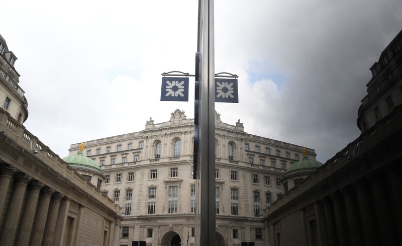 The logo of RBS bank is seen reflected in the windows of a branch of the bank in the City of London financial district in London