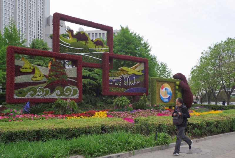 Man walks past a flower installation set up for the upcoming Belt and Road Forum in front of the Chinese Foreign Ministry in Beijing