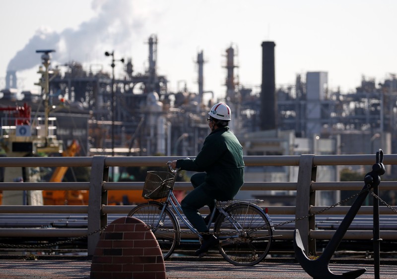 FILE PHOTO: A worker cycles near a factory at the Keihin industrial zone in Kawasaki