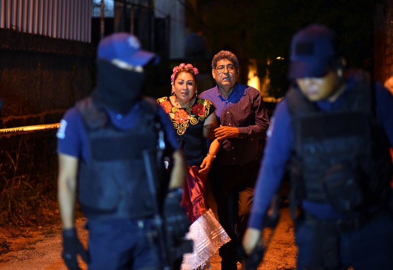 People react next to police officers guarding a crime scene where unidentified assailants opened fire at a bar in Minatitlan