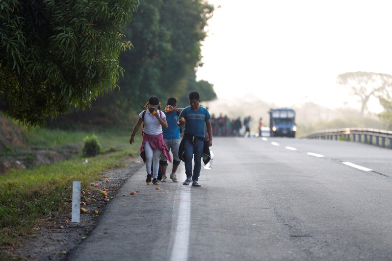 Central American migrants eat mangoes for breakfast as they walk during their journey towards the United States, in Mapastepec