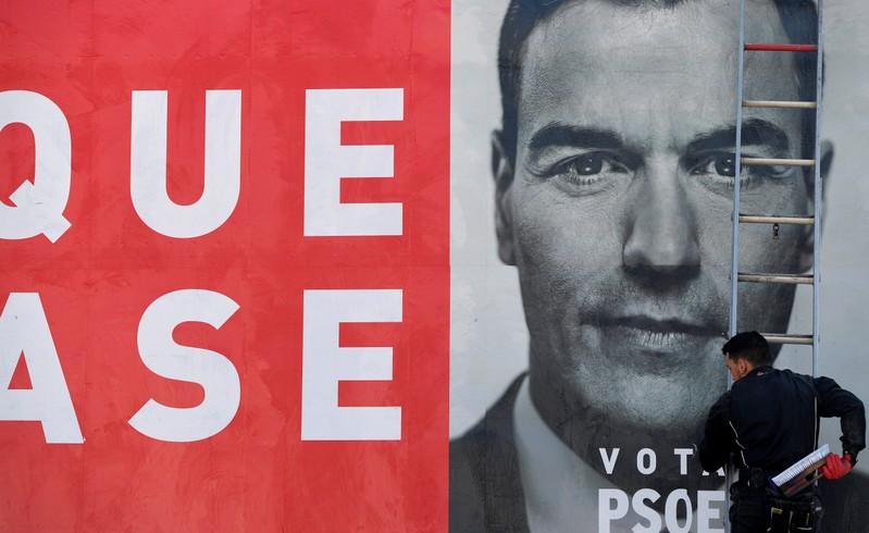 A worker places an electoral poster of Spain's Socialist leader and current Prime Minister Pedro Sanchez in La Fresneda