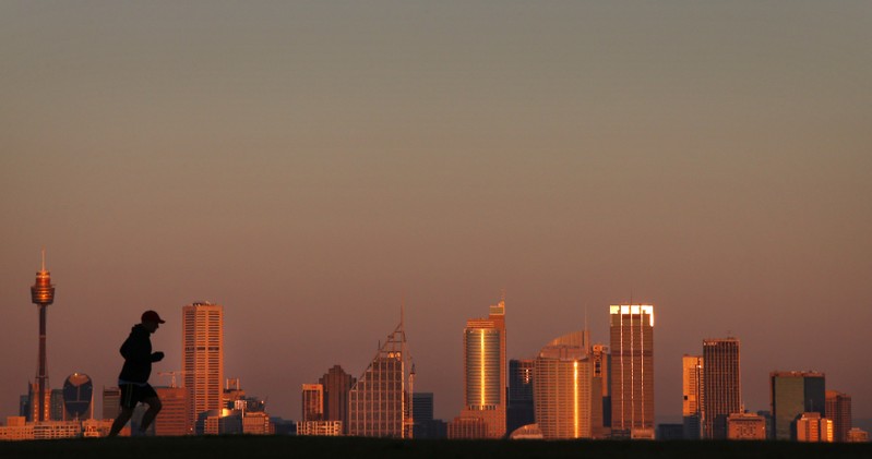 FILE PHOTO - A man runs across a hill in front of the Sydney city skyline under a smoke tinted sky at daybreak