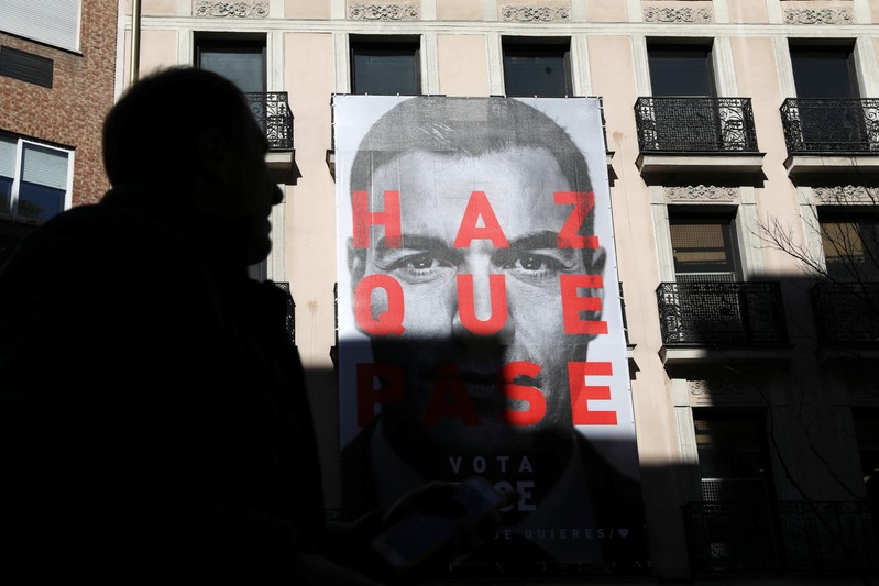 A man walks past an electoral poster of Spain's Socialist (PSOE) leader and current PM Sanchez outside the PSOE headquarters in Madrid