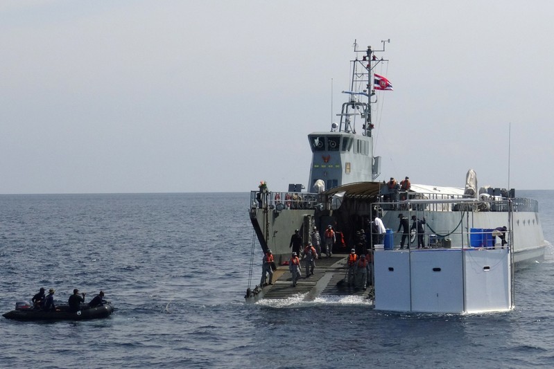 A Royal Thai navy ship drags a floating home, lived in by an American man and his Thai partner, in the Andaman Sea, off Phuket Island in Thailand
