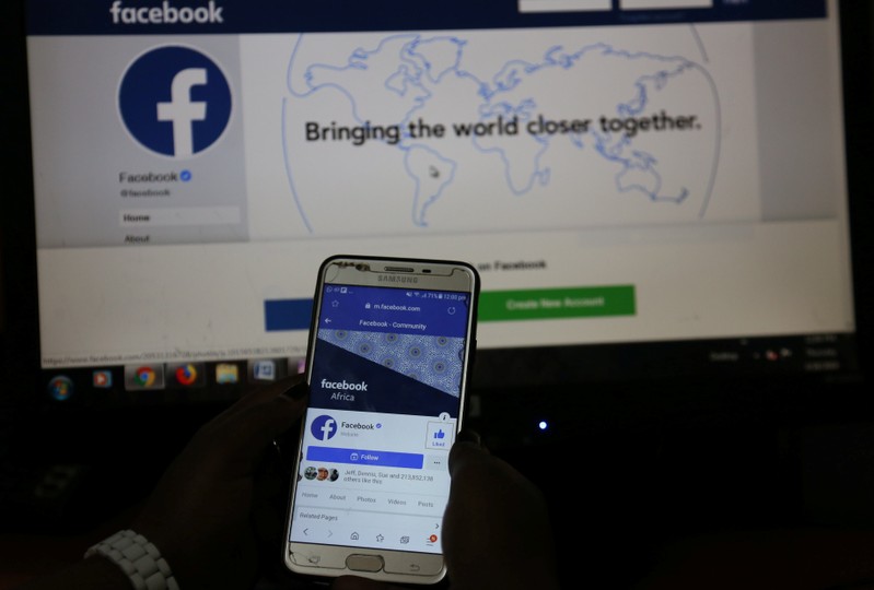 An illustration photo shows the Facebook page displayed on a mobile phone internet browser held in front of a computer screen at a cyber-cafe in downtown Nairobi