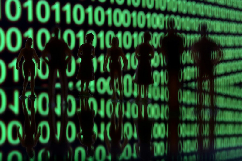 FILE PHOTO: Small toy figures are seen in front of a binary code in this illustration picture