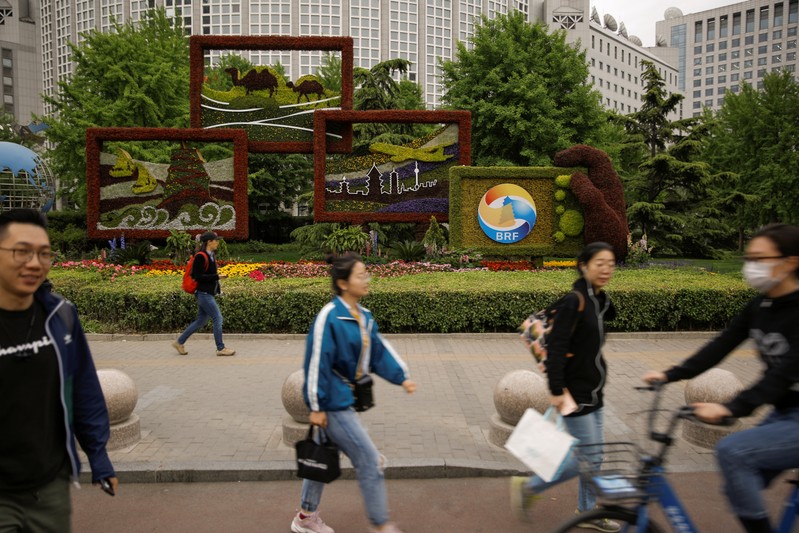 FILE PHOTO: People walk past a flower arrangement set up to mark the upcoming Belt and Road Forum in Beijing
