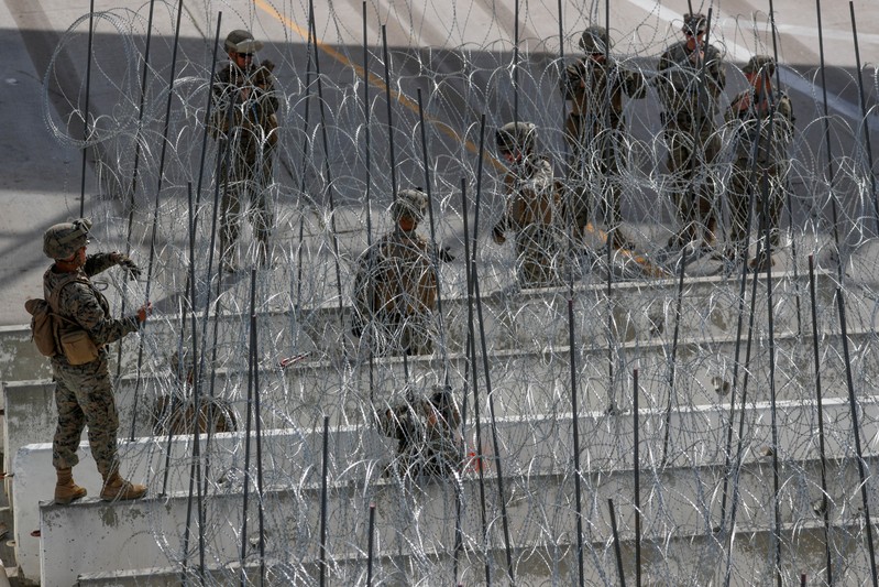 FILE PHOTO: U.S. Marines help to build a concertina wire barricade at the U.S. Mexico border in preparation for the arrival of a caravan of migrants at the San Ysidro border crossing in San Diego