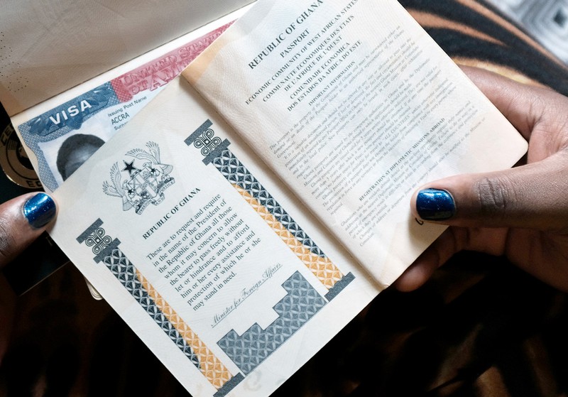 FILE PHOTO: A Ghanian woman poses while holding her family's passports with a U.S. visa in Accra