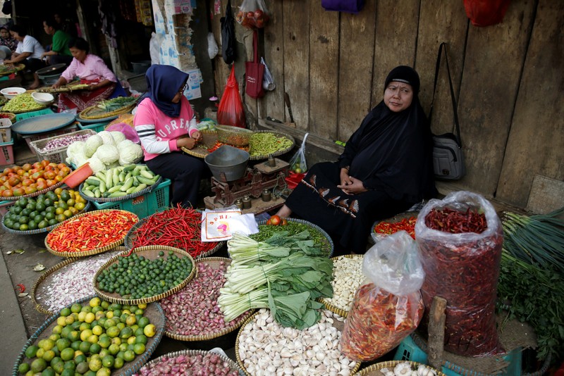 FILE PHOTO: A vegetable seller sits while waiting for customers at the morning market in Jakarta, Indonesia