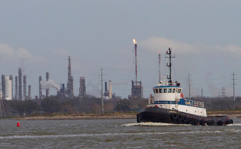 FILE PHOTO: A tug boat navigates the Houston ship channel with a flare from an oil refinery and storage facility in the background south of downtown Houston
