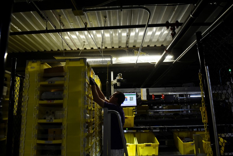 Worker takes products for delivery from a robotic shelf at the Amazon fulfilment center in Baltimore