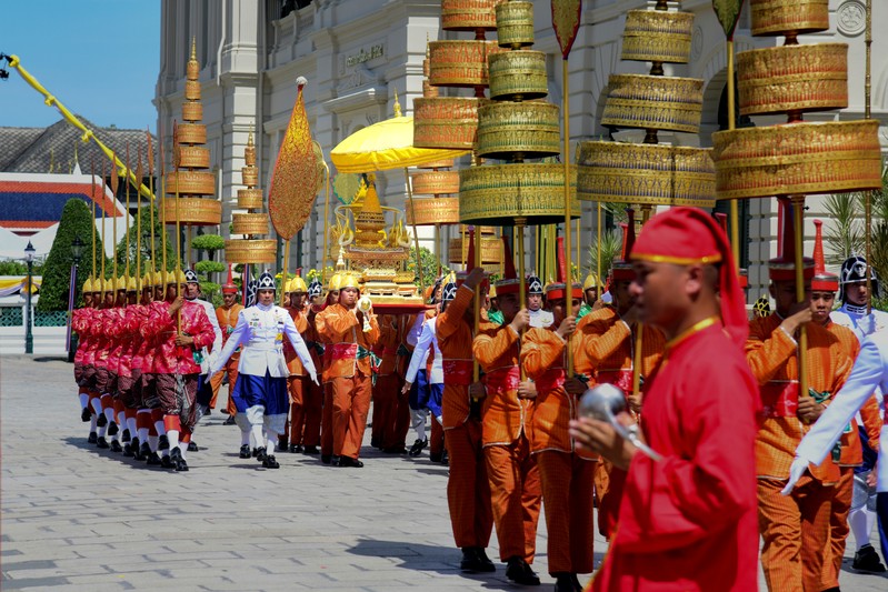 Thai soldiers dressed in traditional costumes transfer The Royal Golden Plaque of the official title of His Majesty the King, the Royal Golden Plaque of His Majesty's horoscope, and the Royal Seal of State to Baisal Daksin Throne Hall at the Grand Palace