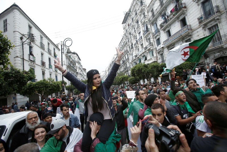 Demonstrators hold flags and banners during peaceful anti-government protests in Algiers