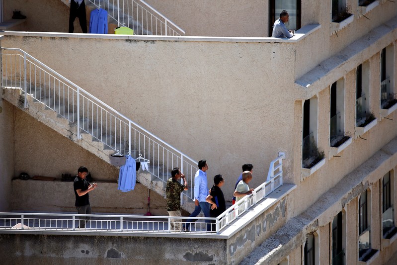 Chinese workers look on as an Iron Dome anti-missile projectile intercepts a rocket that was fired from Gaza, above the Israeli city of Ashkelon