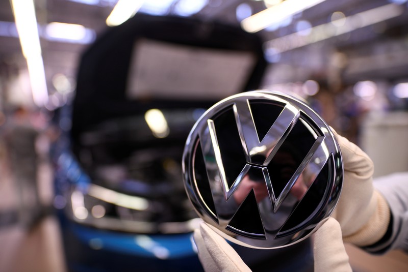 FILE PHOTO: An employee holds a Volkswagen logo in a production line at the Volkswagen plant in Wolfsburg