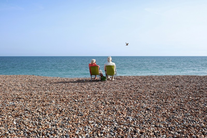 FILE PHOTO: FILE PHOTO: A couple sit on the beach and look out to sea on the August bank holiday weekend in Worthing