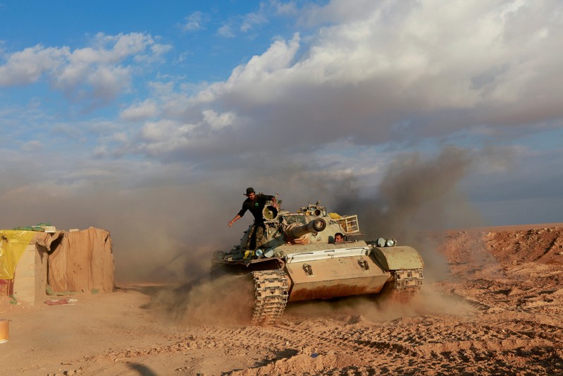 FILE PHOTO: PMF fighters ride in a tank near the Iraqi-Syrian border in al-Qaim, Iraq.