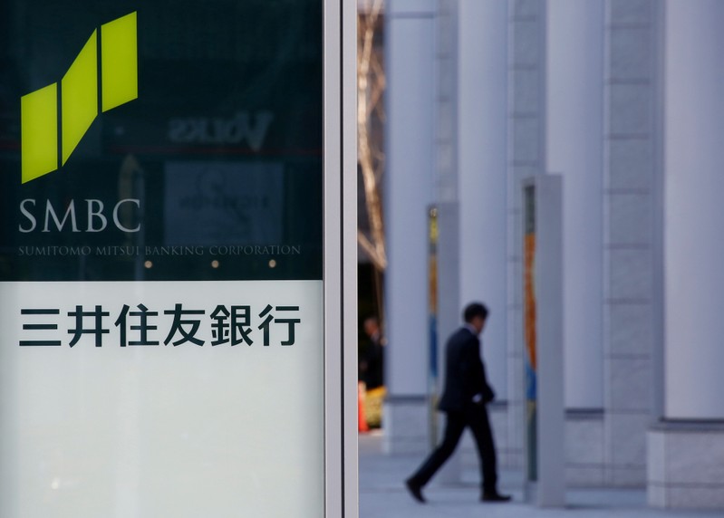 FILE PHOTO: Workers clean windows next to a signboard of Sumitomo Mitsui Financial Group's SMBC Friend Securities in Tokyo
